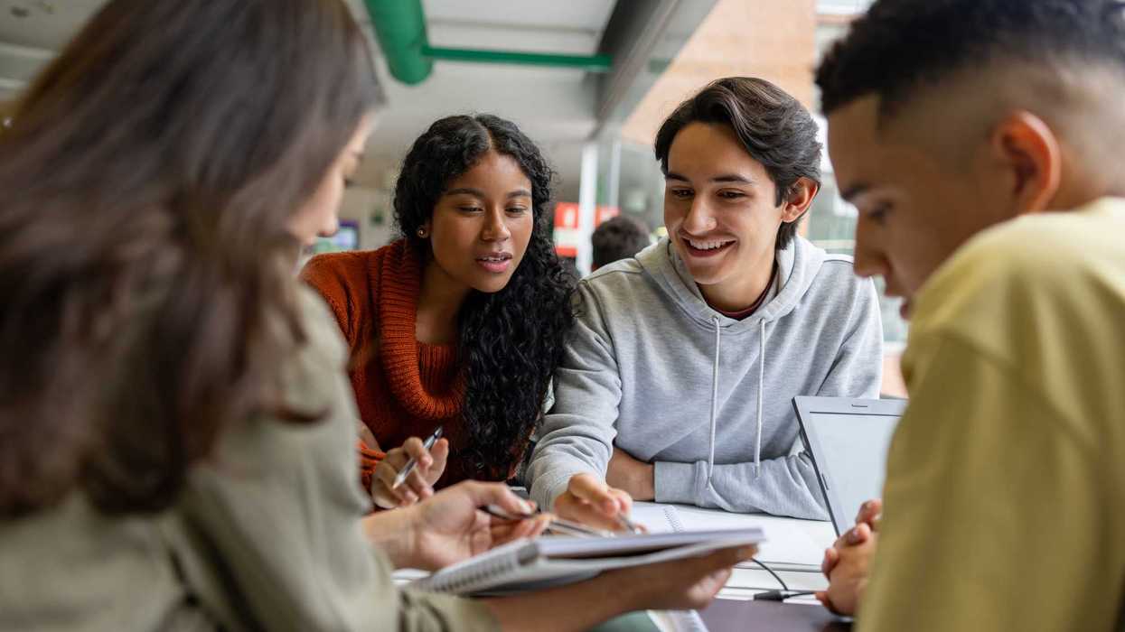 Happy Latin American group of students studying together at the library
