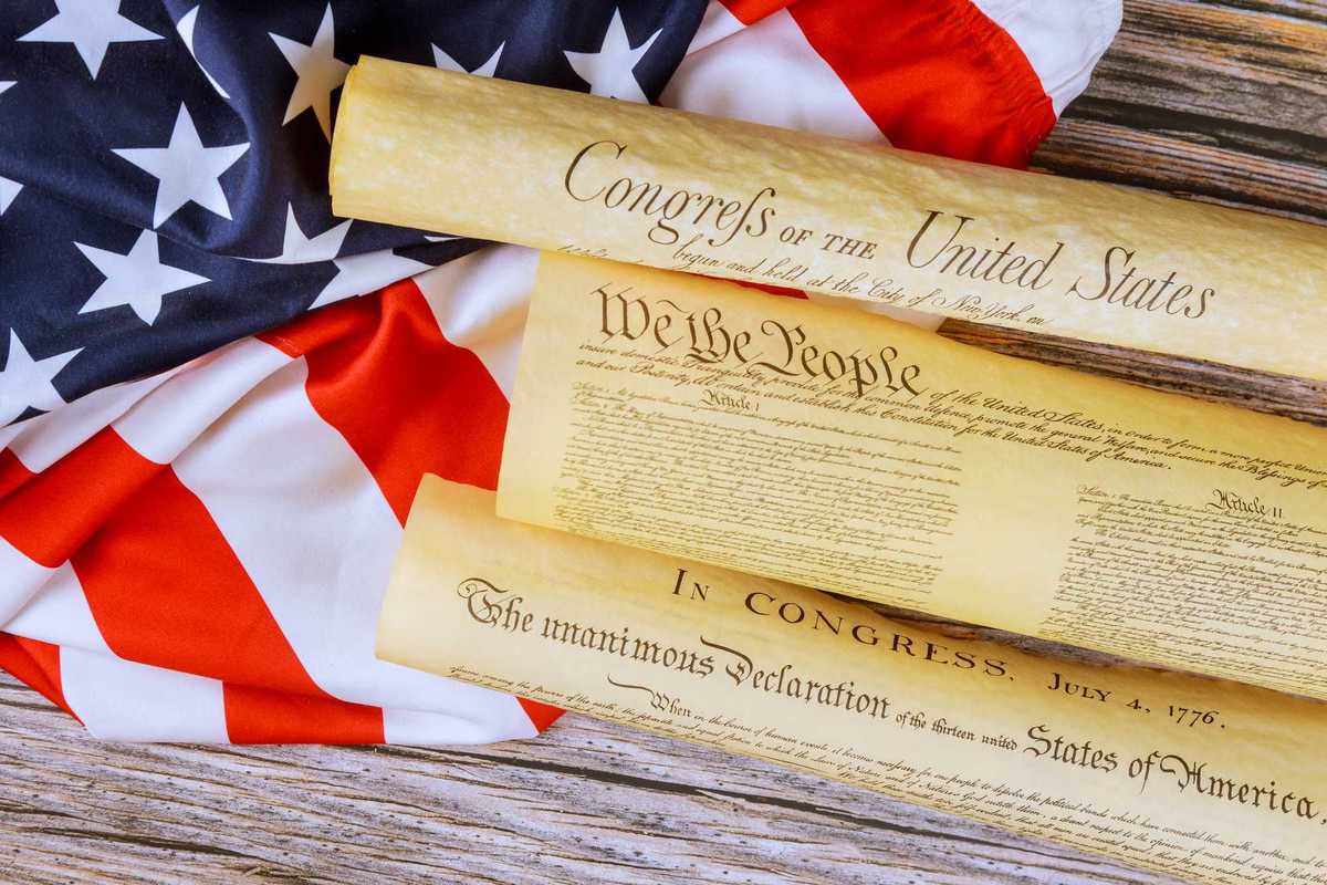 Historical documents representing founding principles of United States on flag backdrop