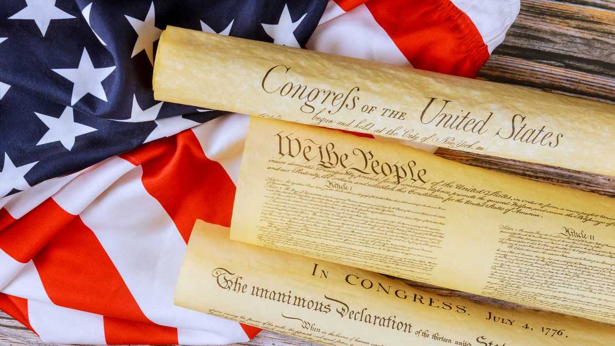 Historical documents representing founding principles of United States on flag backdrop