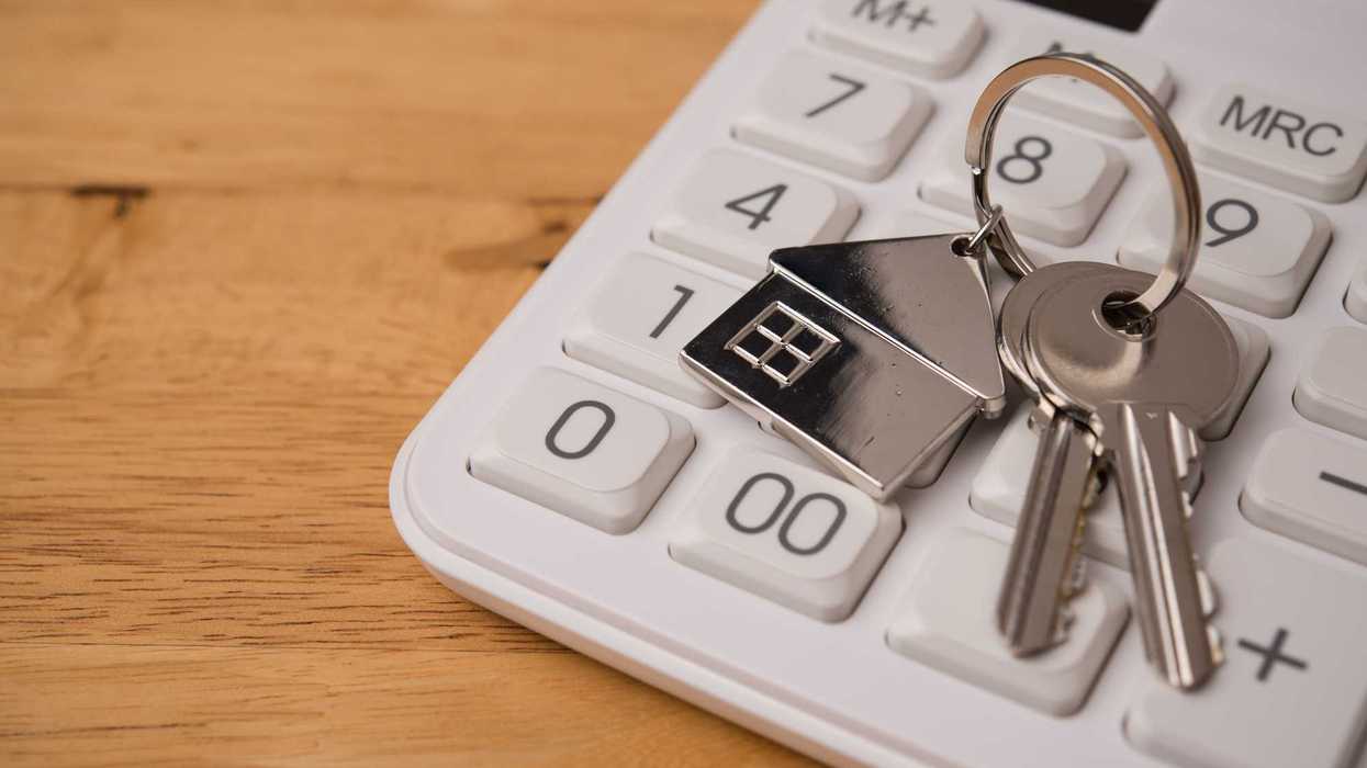 House key on calculator with wooden table background copy space.
