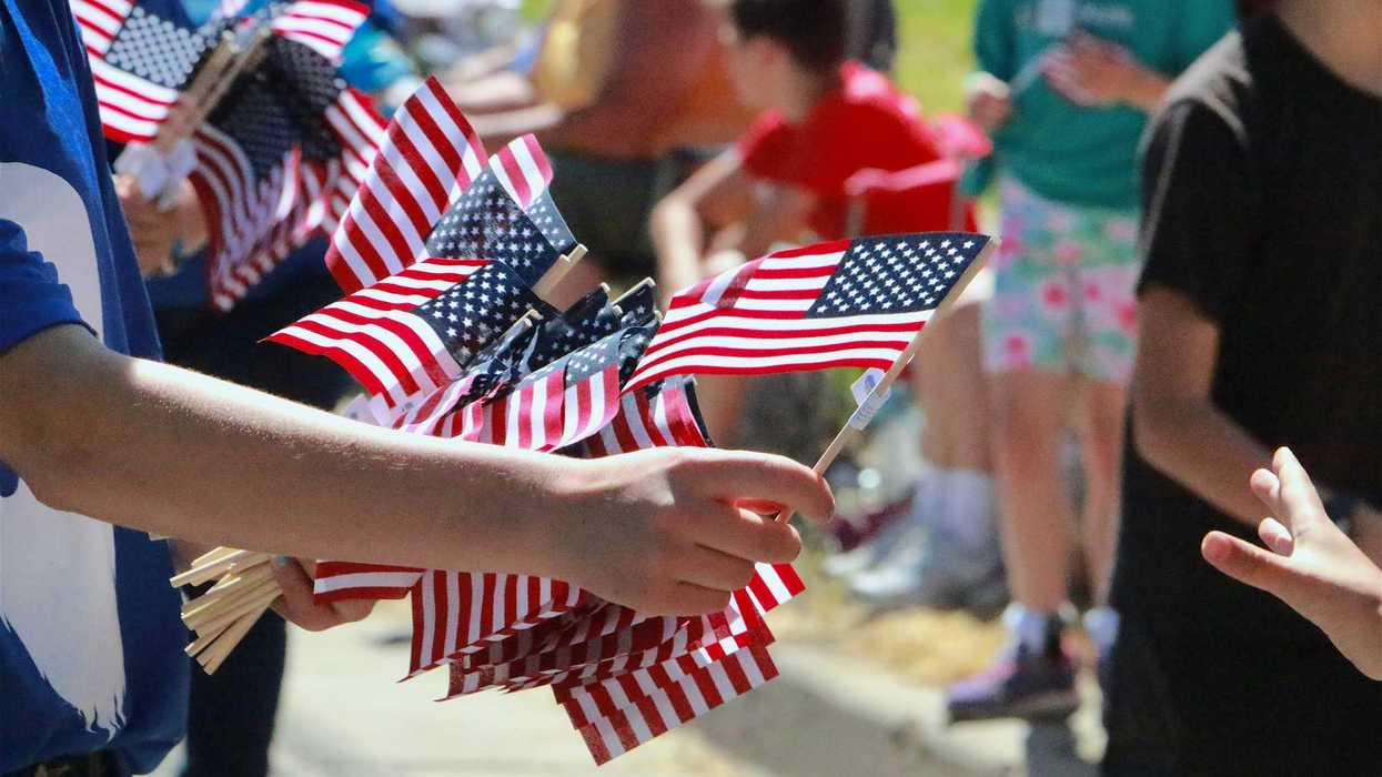 Human Hand Passing Out American Flags Parade Route Blurred Crowd in Background