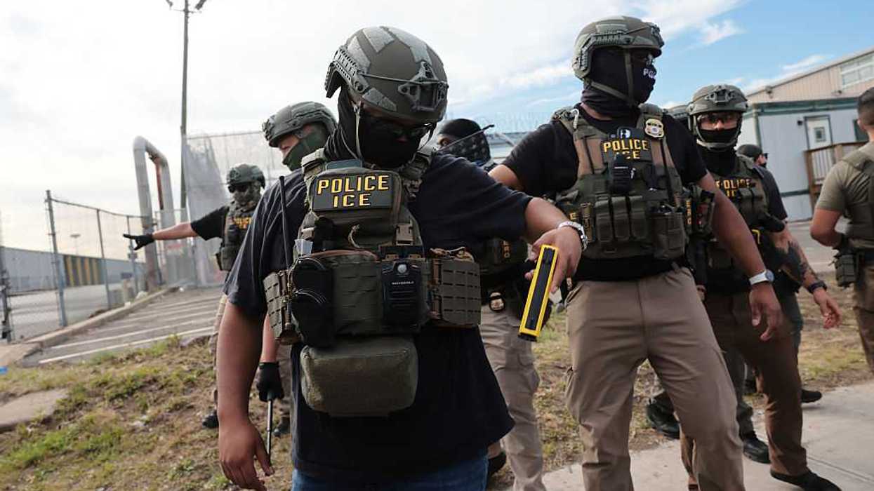 ICE agents wearing gear that reads, "POLICE ICE." Their faces are covered, they are wearing helmets, and one of them is holding a weapon.
