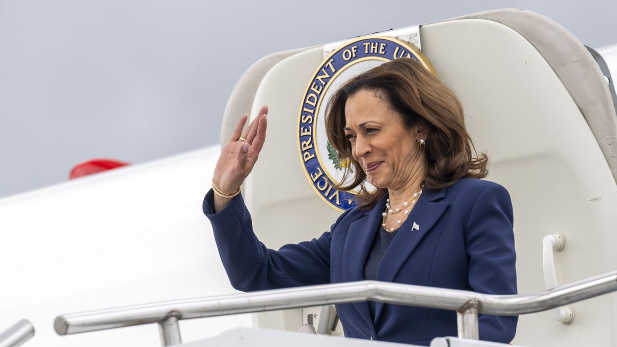 Kamala Harris waiving as she exits an airplane