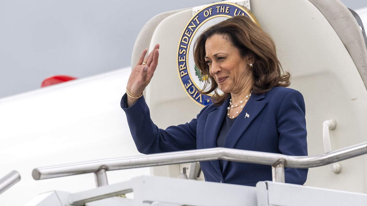 Kamala Harris waiving as she exits an airplane