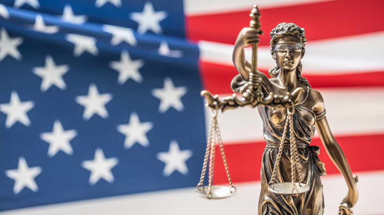 Lady of Justice in front of a U.S. flag.
