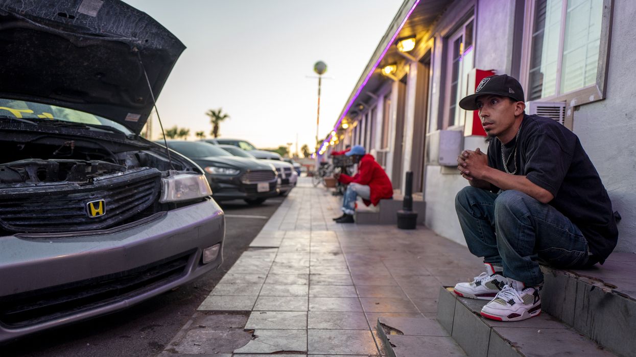 Latino man sitting outside a motel room