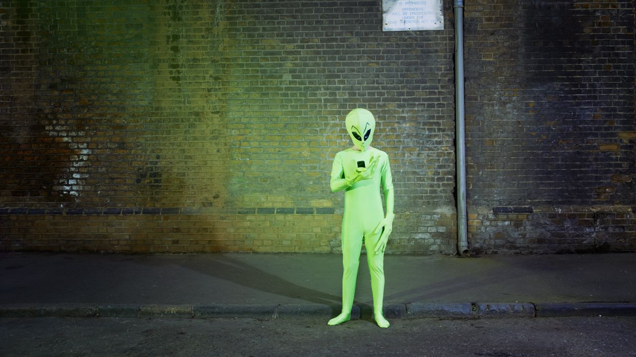 Man dressed in alien costume looking at mobile phone