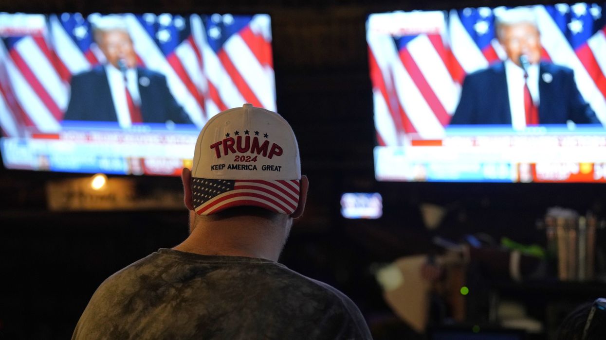 Man wearing Trump hat watches Trump on TV