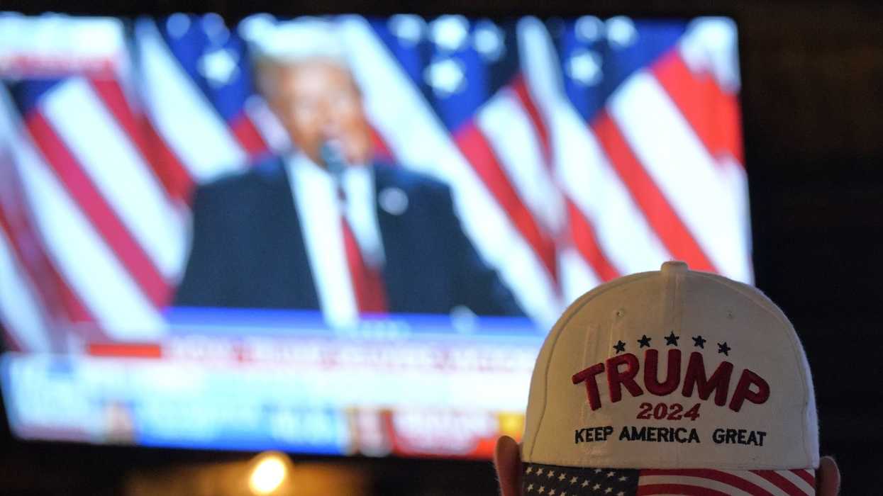 Man wearing Trump hat watches Trump on TV