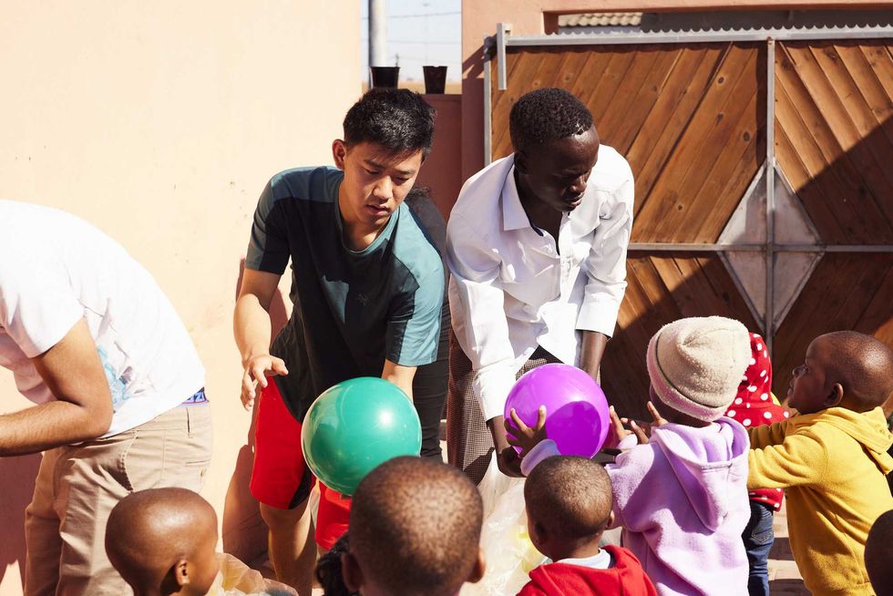 men giving young children balls to play with