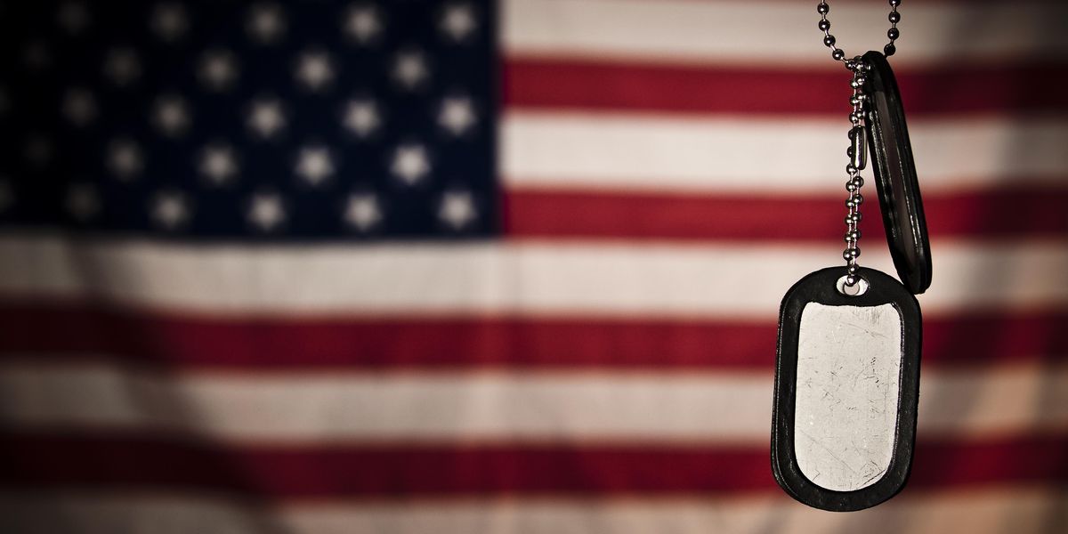 Military dog tags hanging in front of a flag