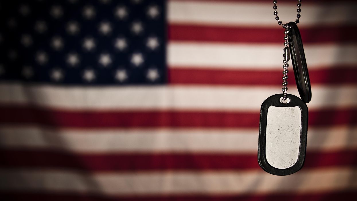 Military dog tags hanging in front of a flag