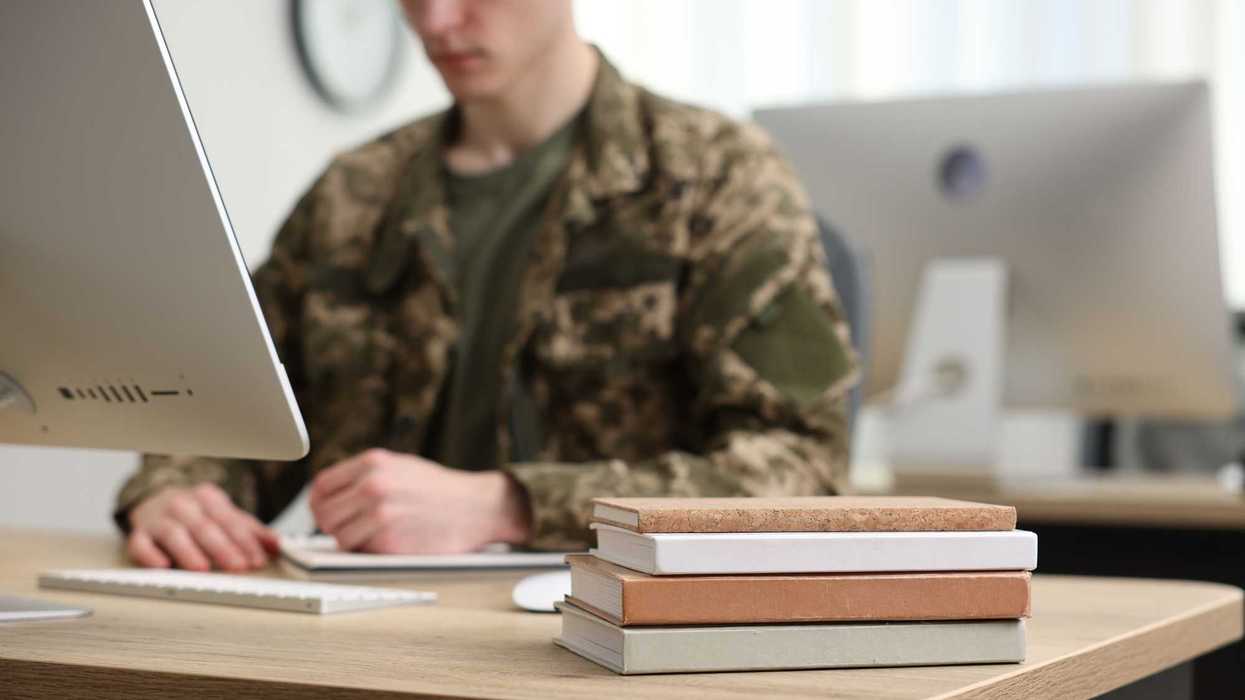 Military education. Student in soldier uniform learning at wooden table indoors, selective focus