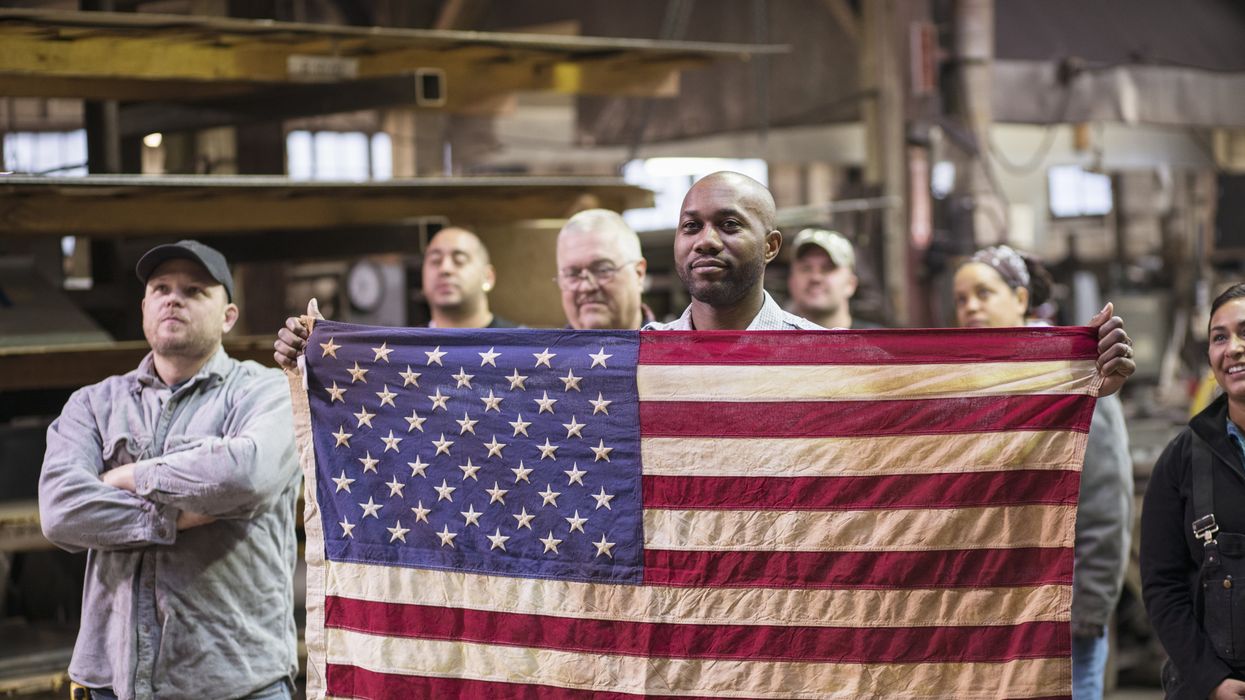 Peope standing togther behind an American flag