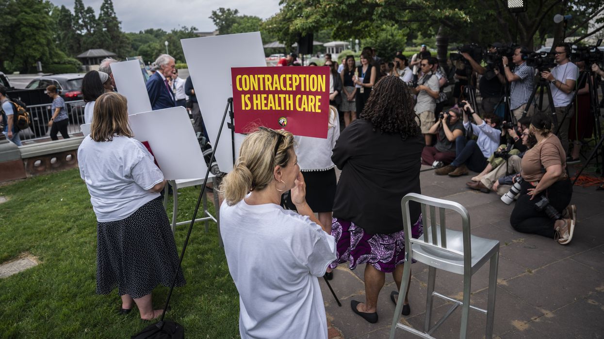 People at a press conference. One has a sign that reads "Contraception is health care."