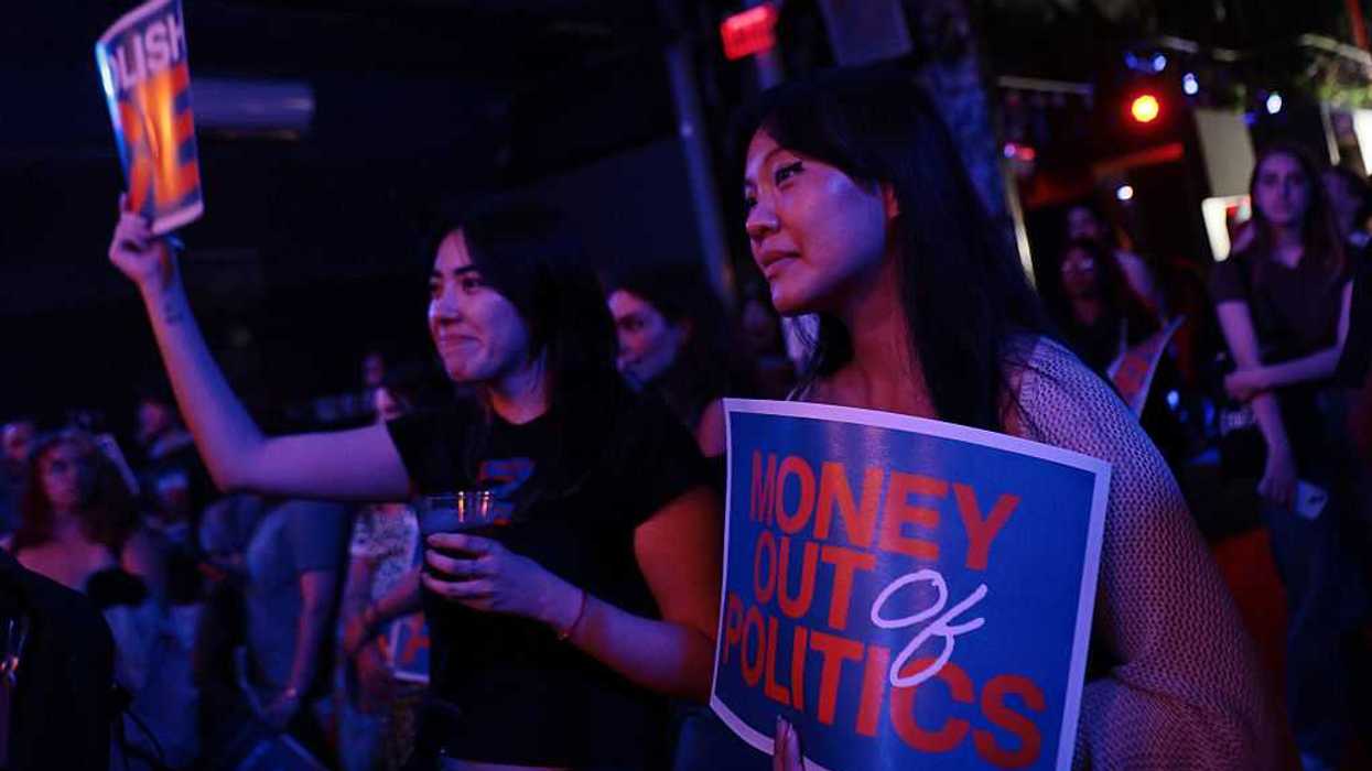People attend a rally with signs that read, "Abolish ICE," and "Money out of politics."
