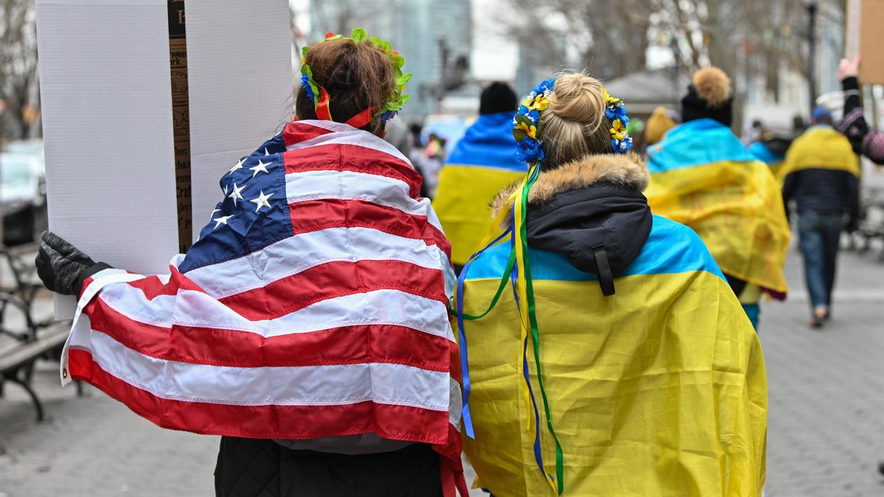 People draped in an American flag and a Ukrainian flag.