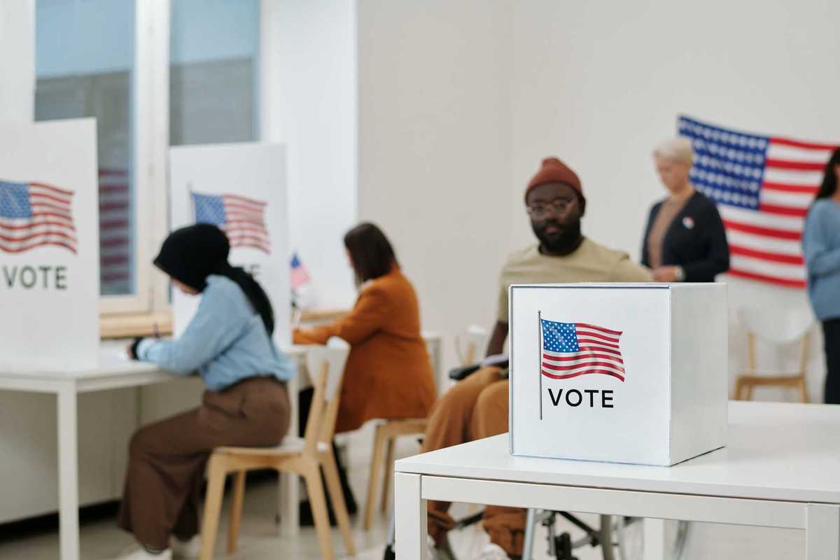 people filling out their ballots at voting booths and submitting their vote.