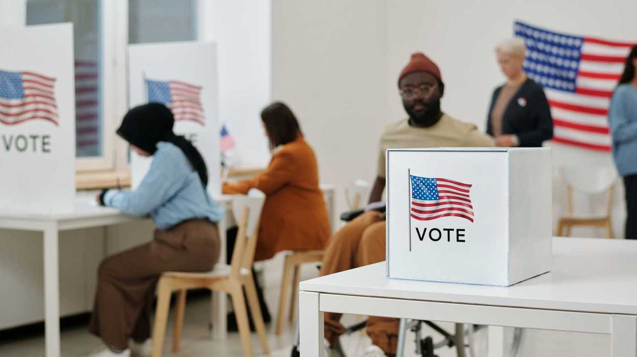 people filling out their ballots at voting booths and submitting their vote.