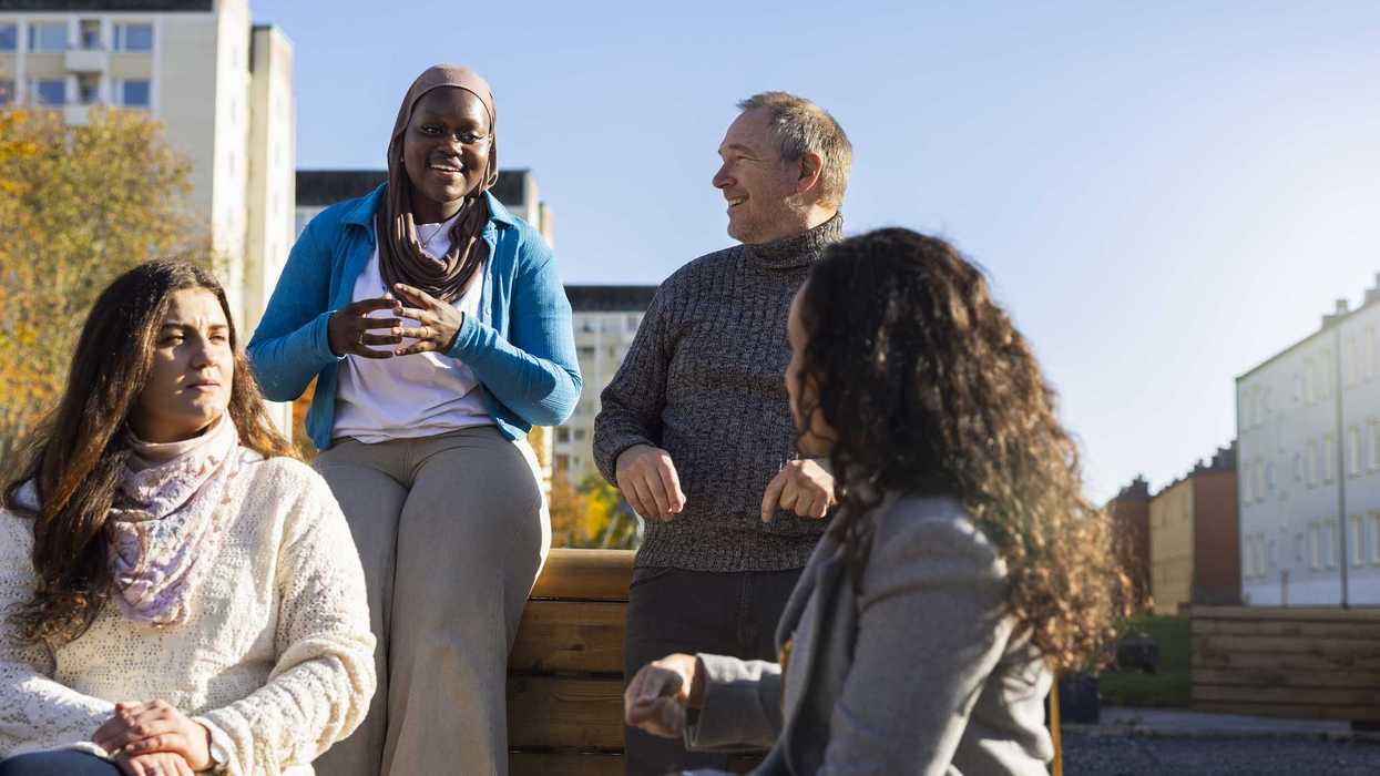 People gathered together, speaking to each other while sitting outside.