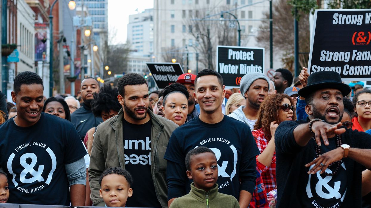 People marching in And Campaign shirts and carrying signs that read "Protect Voter Rights"