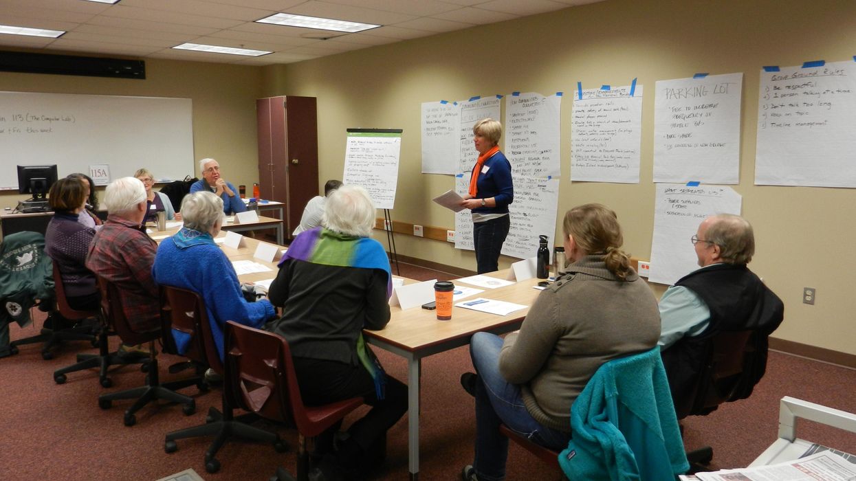 People sitting around a conference table with a moderator taking notes on the wall