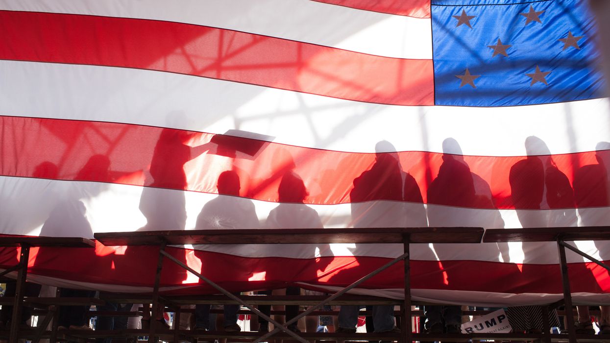 People sitting behind a giant American flag.