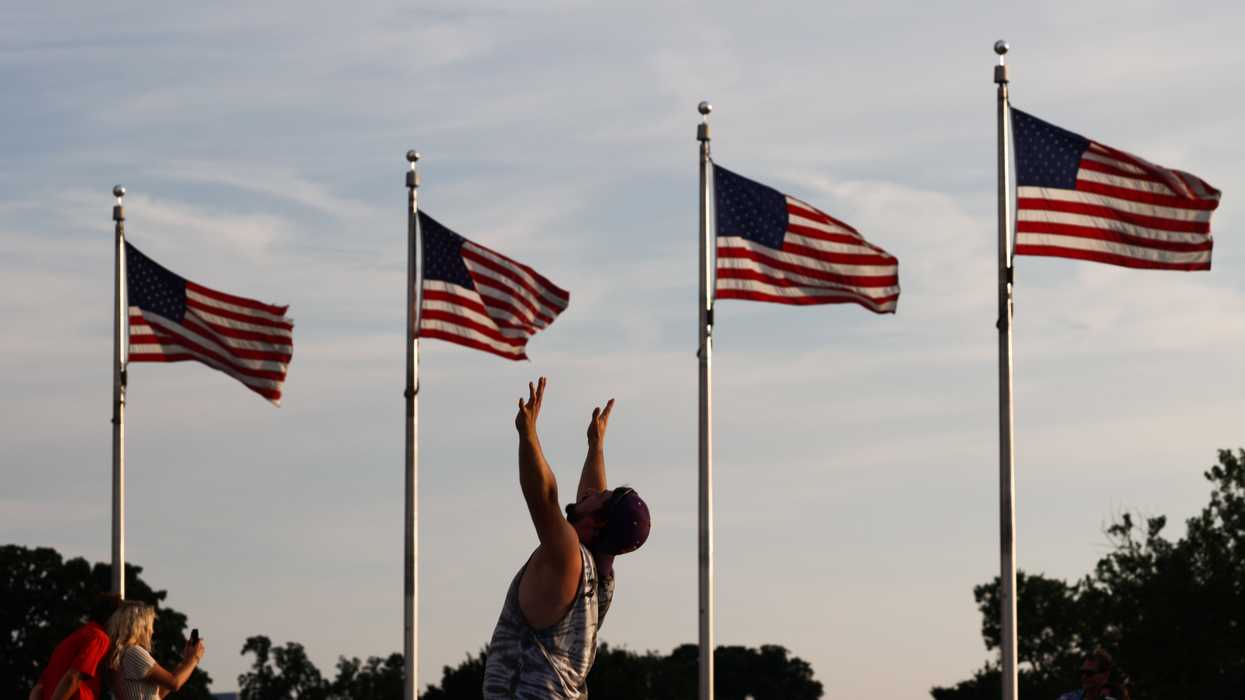 People standing near 4 American flags