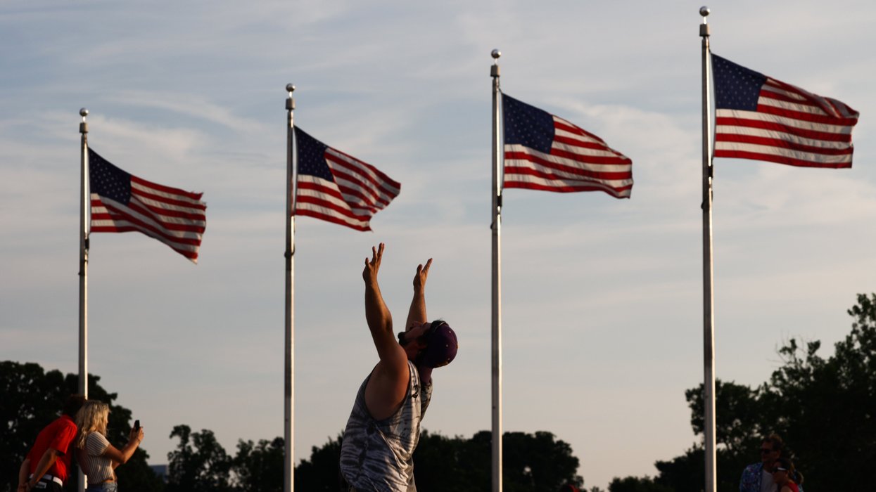 People standing near 4 American flags