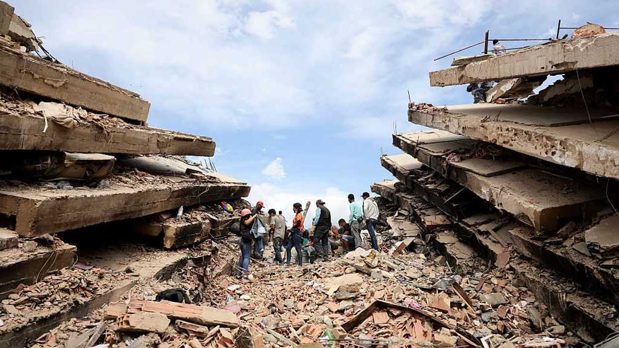 People standing outside between falling buildings.