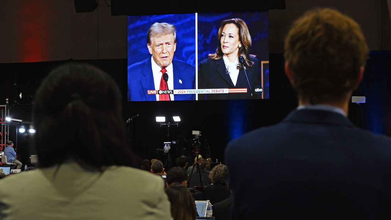 People watching a TV showing Trump and Harris