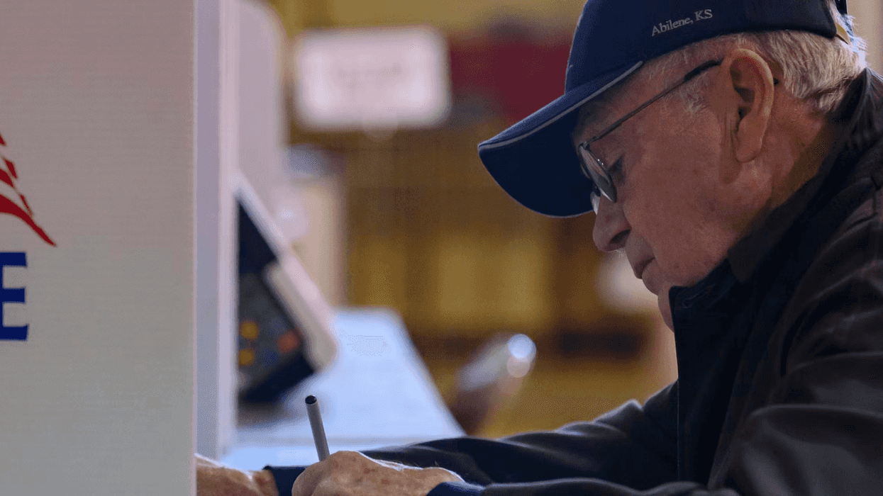 Person at a voting booth, filling out a ballot.