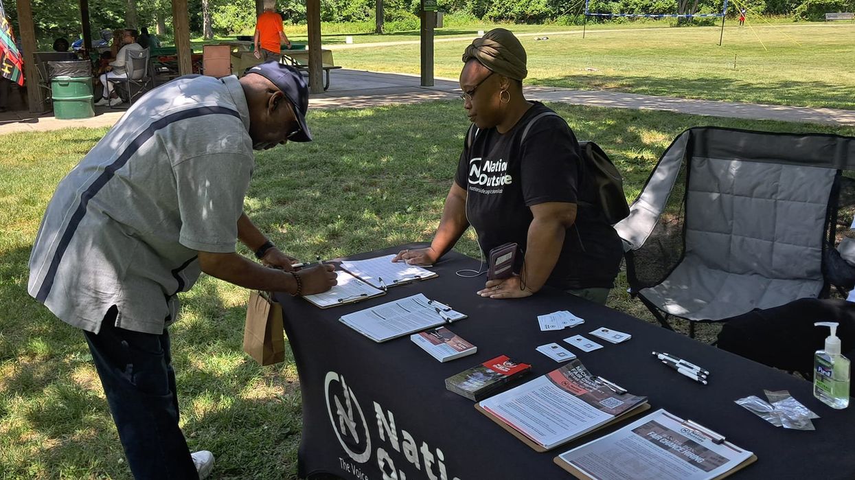 Person filling out a form at a Nation Outside table