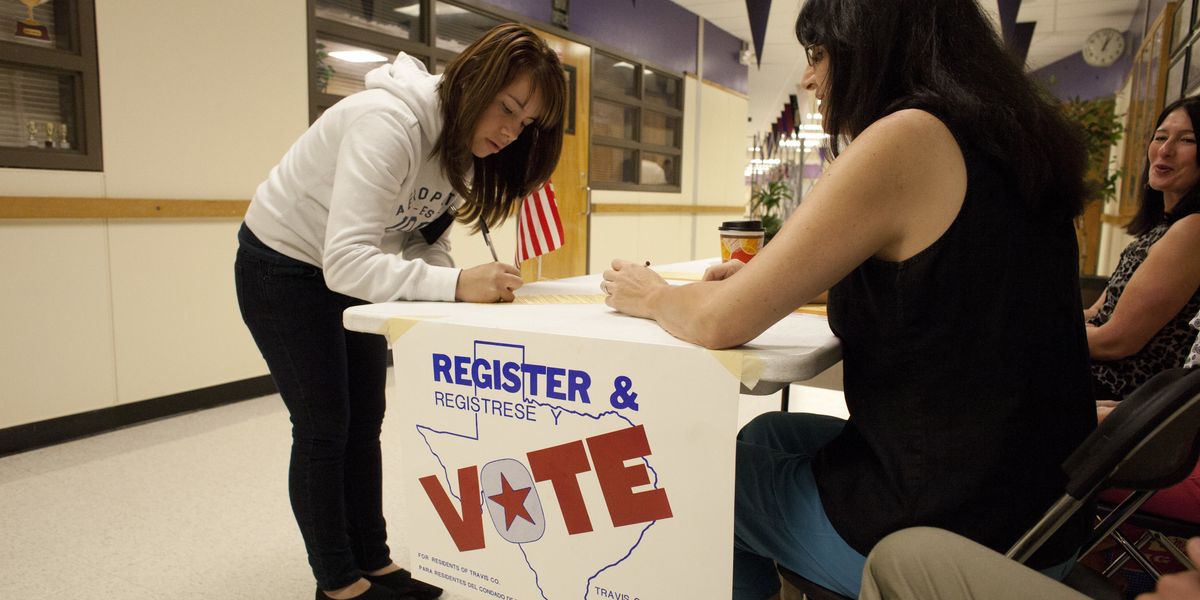 Person filling out paperwork at a voter registration table