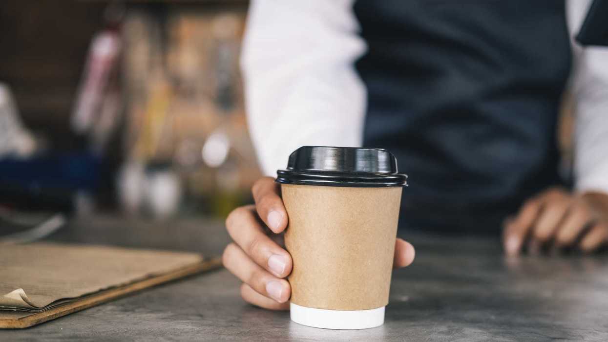 Person hands out a cup of coffee.