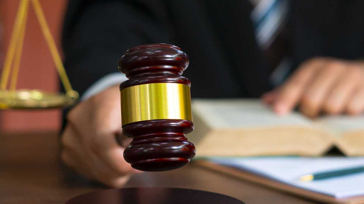Person holding gavel and reading from a book.