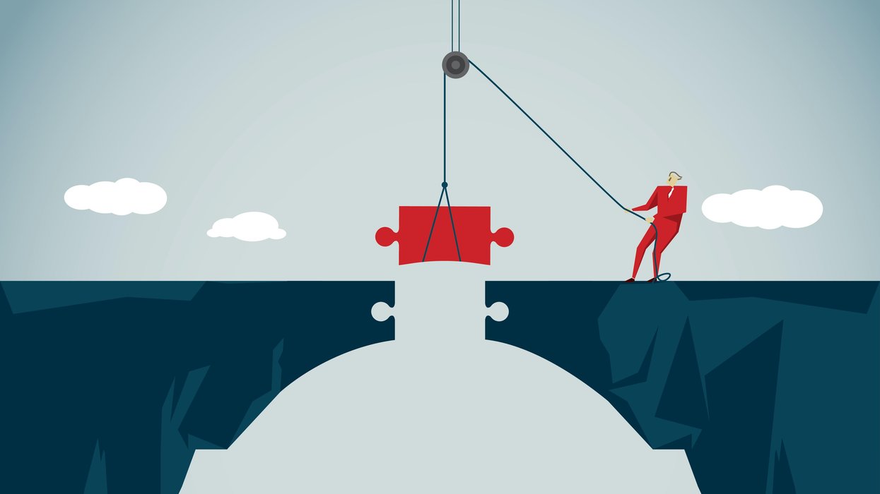 Person inserting a puzzle piece to finish a bridge