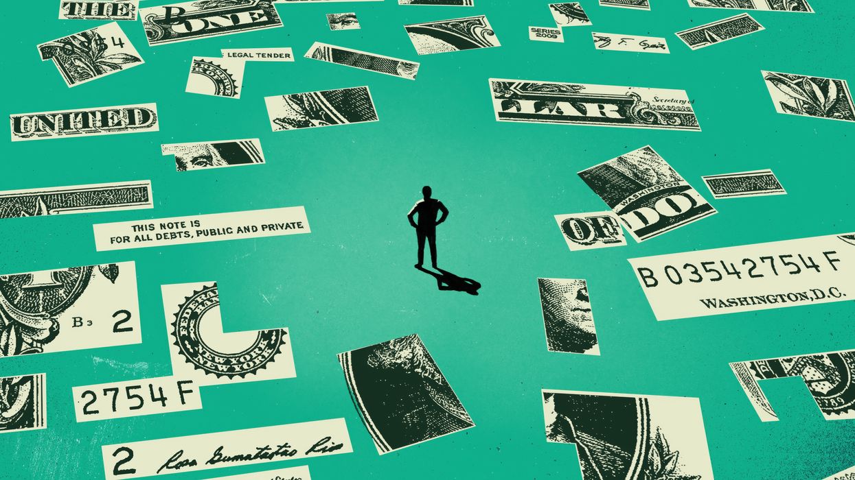 Person standing amid pieces of a cut-up dolalr bill