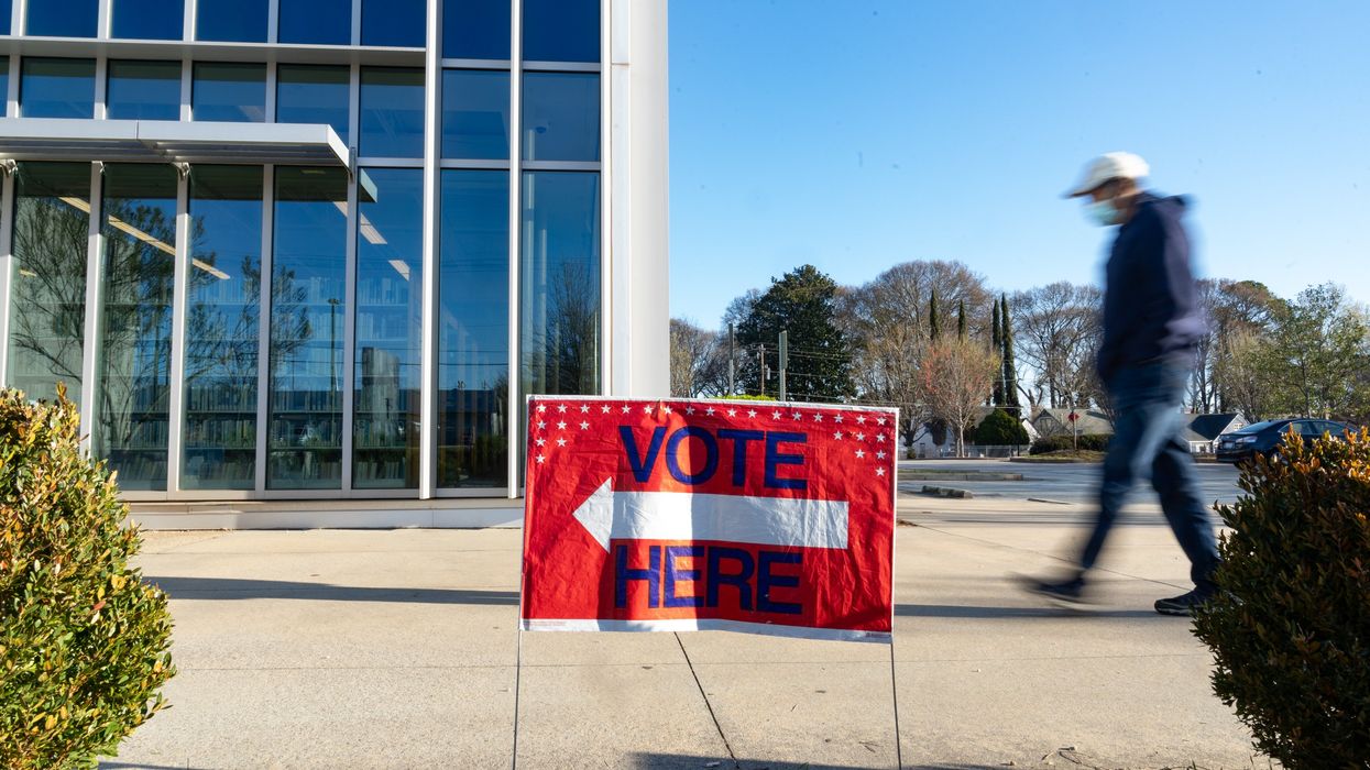 Person walking past a "Vote Here" sign