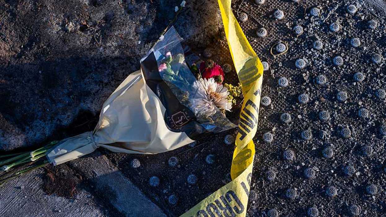 Police tape and a batch of flowers lie at a crosswalk.