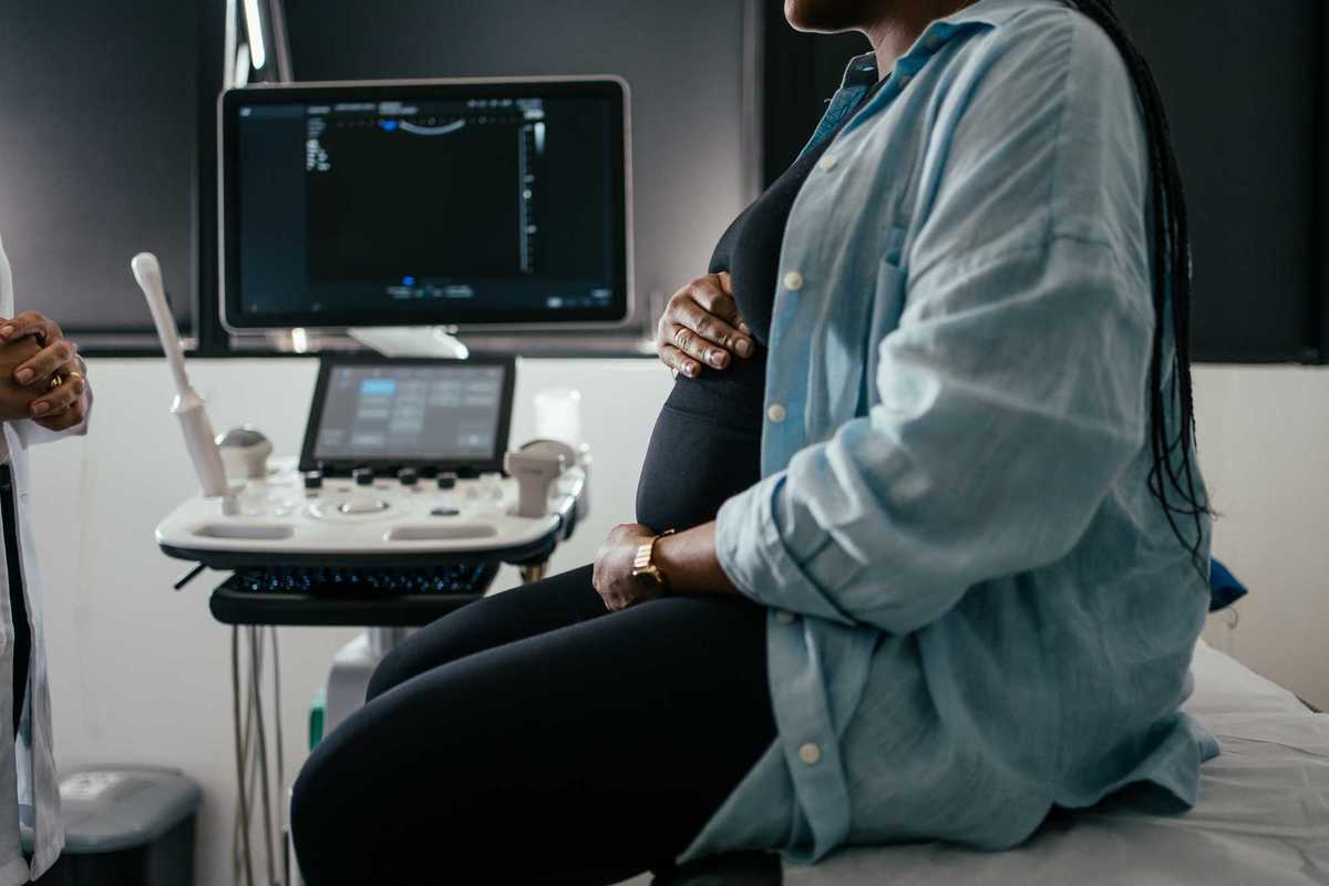 Pregnant woman holding her belly during a prenatal exam.