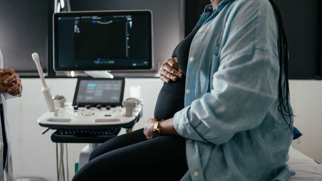 Pregnant woman holding her belly during a prenatal exam.