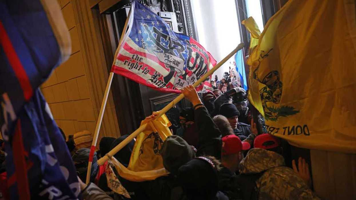 Protesters breaking into the U.S. capitol on Jan. 6, 2021, holding flags.