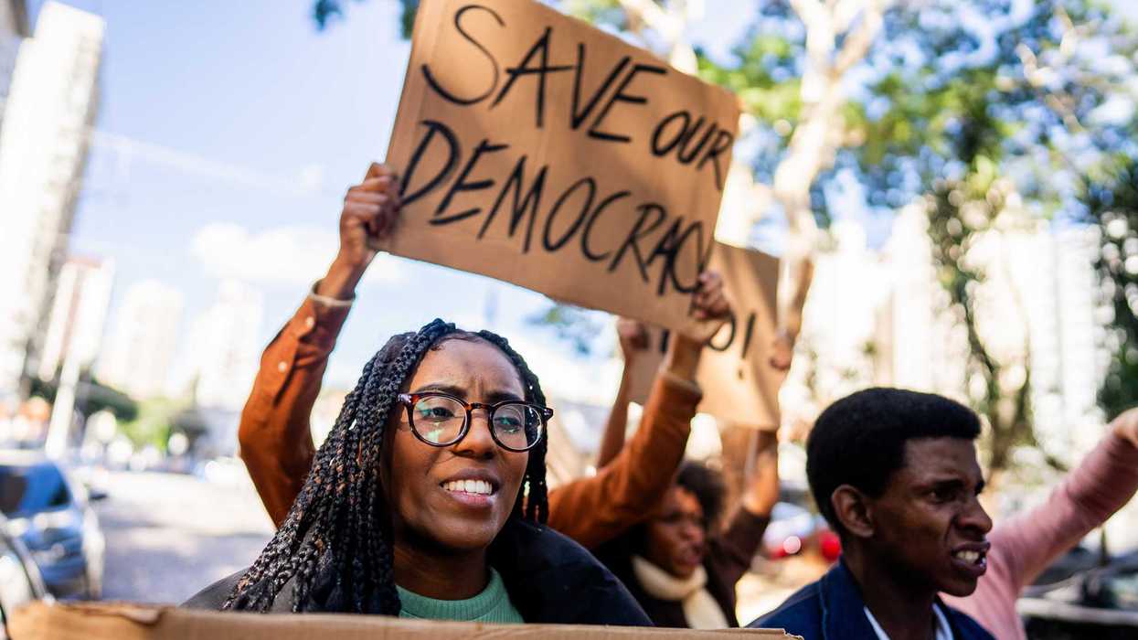 Protestors holding a "save our democracy," sign.