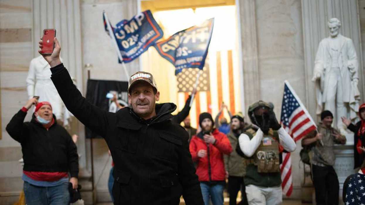 Protestors holding flags that read, "Trump 2020," and recording on their phones inside the U.S. Capitol.