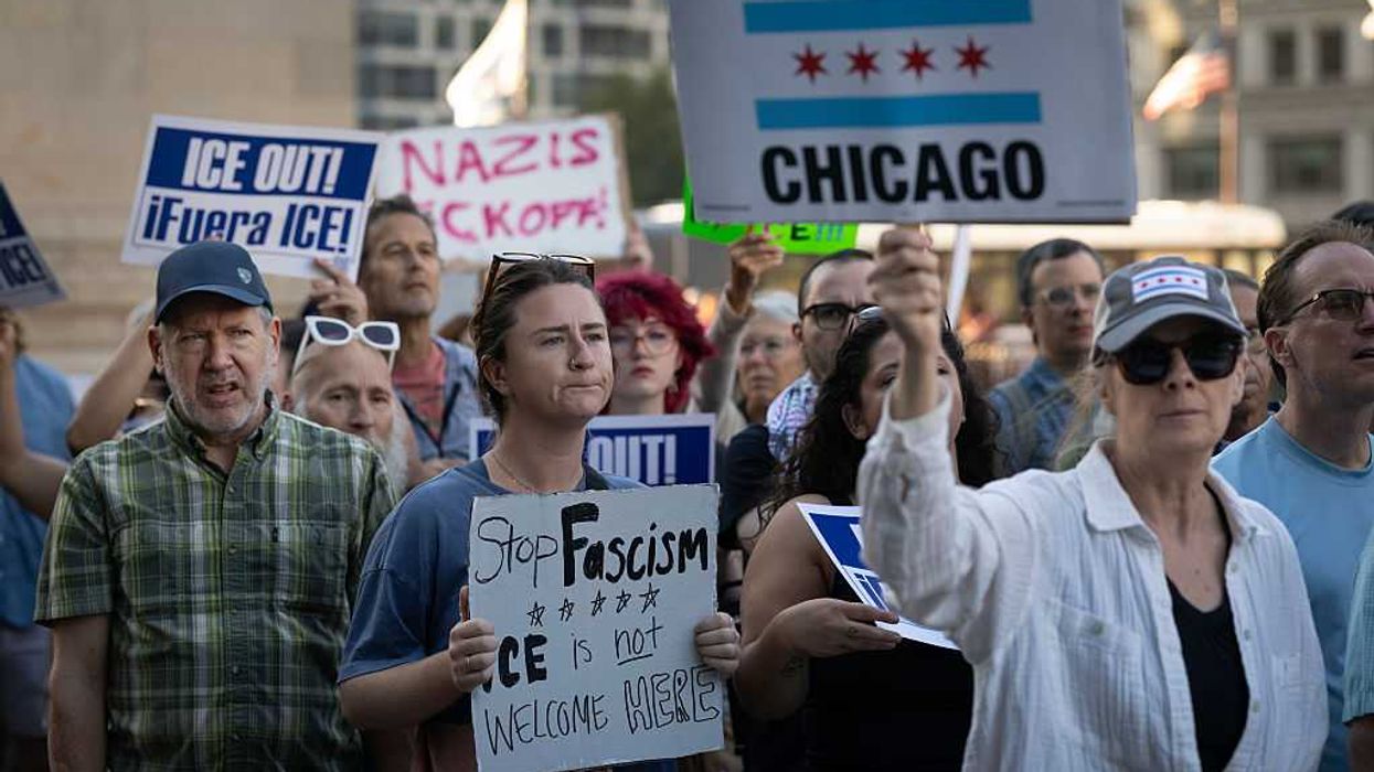 Protestors holding signs at a rally in Chicago against ICE.
