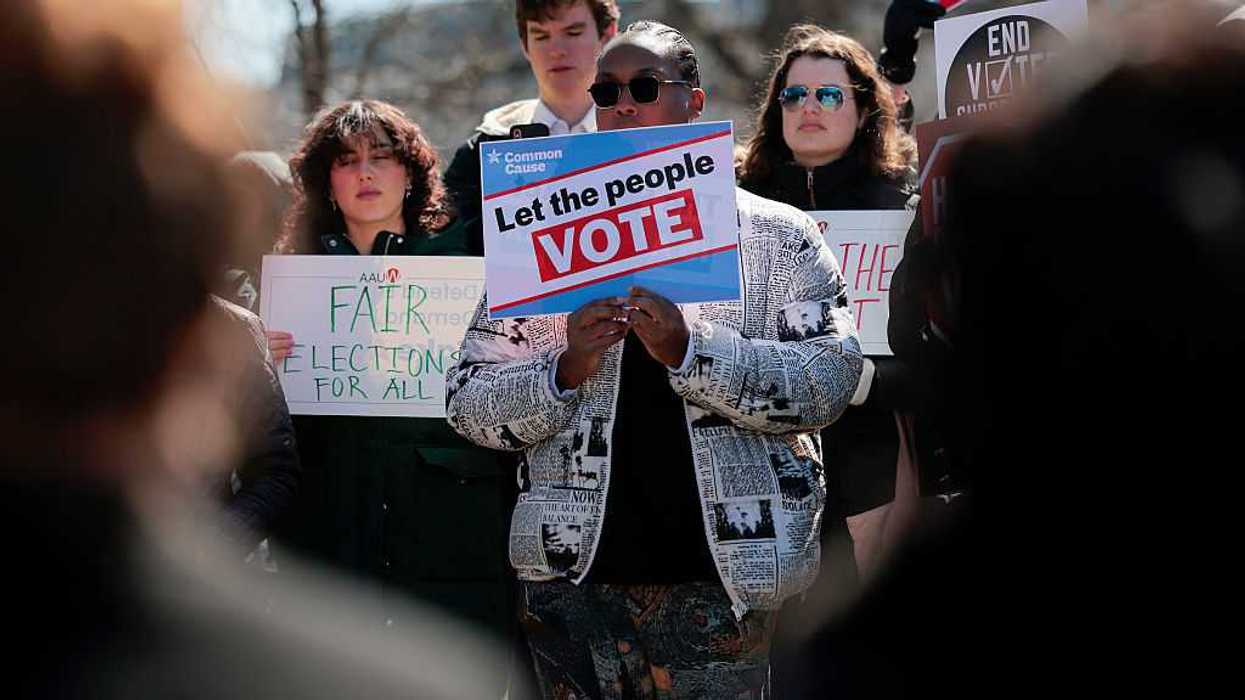 Protestors holding signs, including one that says "let the people vote."