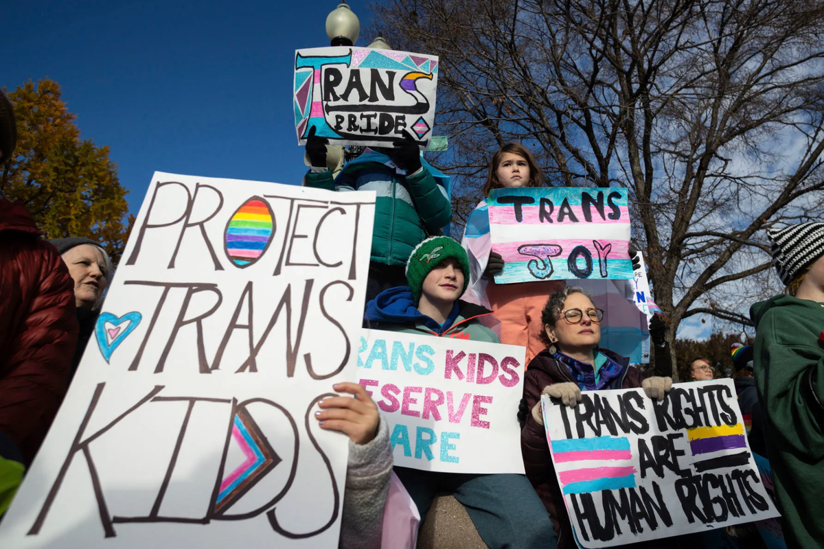 Protestors holding signs that read "protect trans kids."