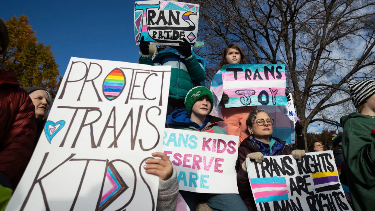Protestors holding signs that read "protect trans kids."