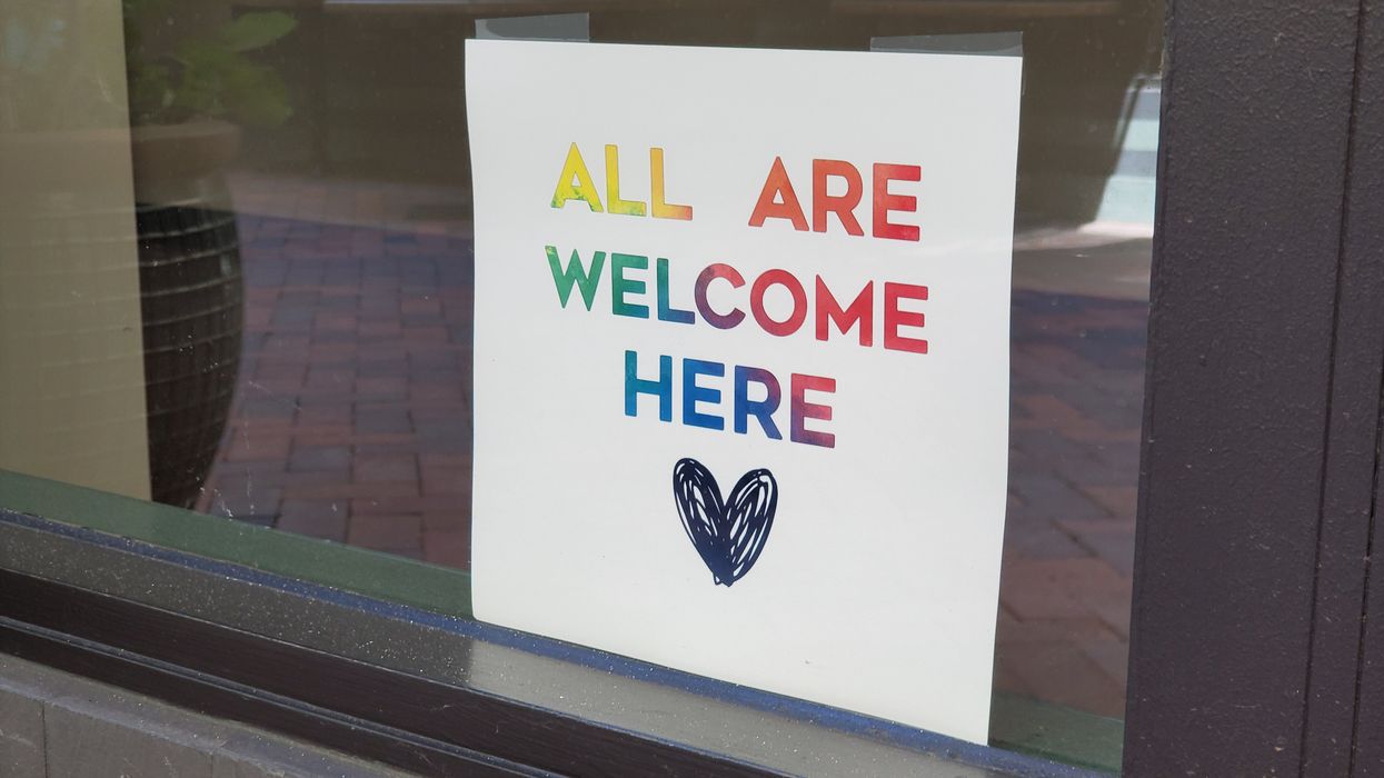 Rainbow sign that reads "All Are Welcome Here"